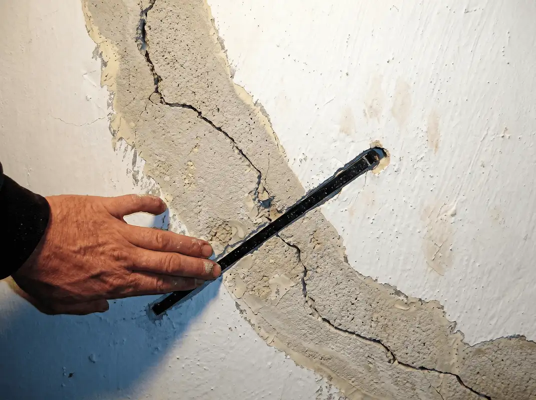 A wall with a large crack is being inspected by a professional in Naperville, IL